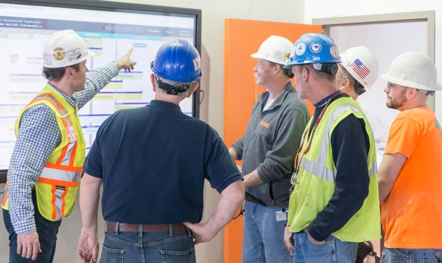 BOND staff with subcontractors in front of a large flat screen TV looking at a schedule together for a pull planning session.